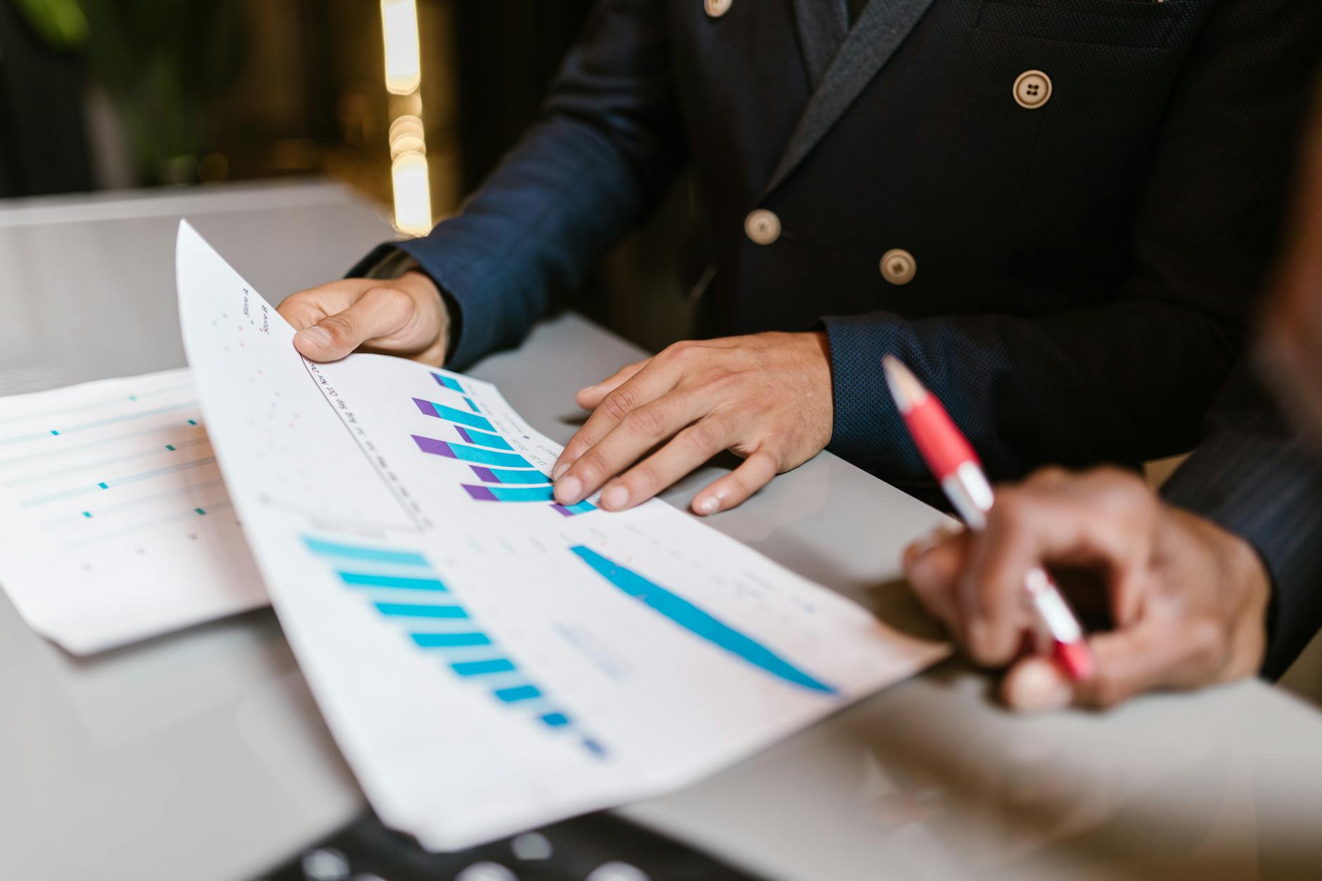 Close-up of professionals reviewing financial graphs at a business meeting. — pijushsaha.com