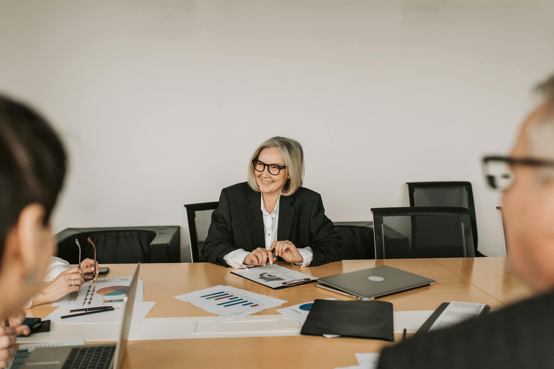 A professional business meeting with diverse professionals discussing reports in a modern office setting. — pijushsaha.com