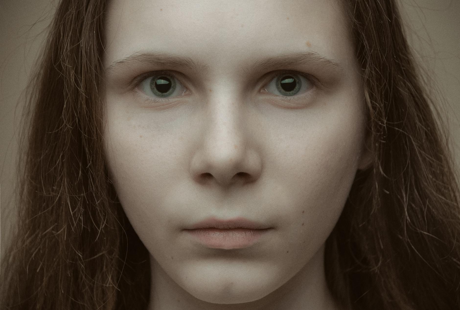 Intimate close-up portrait of a young woman with a neutral expression and long hair. -- pijushsaha.com