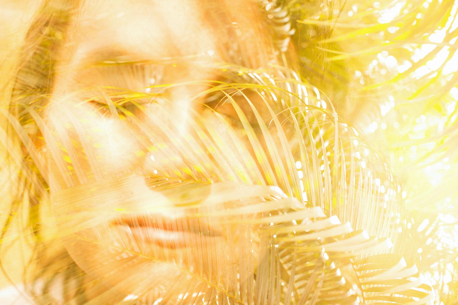 Artistic image of a woman with palm leaves, creating a dreamy effect through double exposure. -- pijushsaha.com