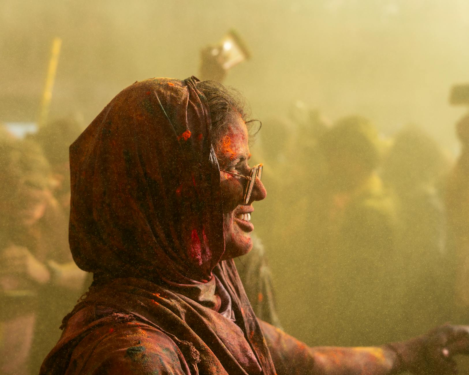 A vibrant scene of Holi celebration in Nandgaon, India showing participants covered in colorful powder. -- pijushsaha.com