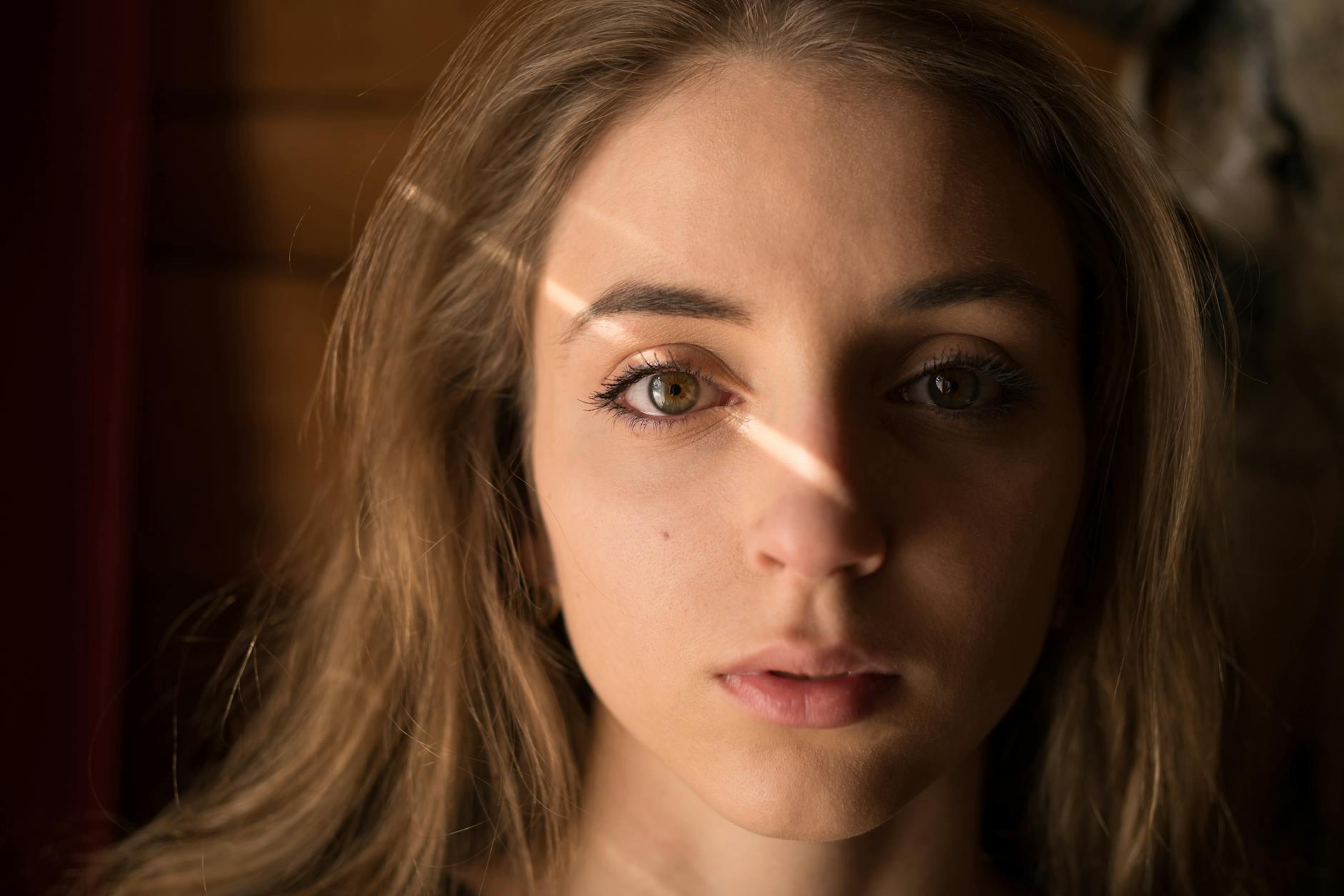 Captivating close-up portrait of a young woman with natural lighting creating a dramatic effect. -- pijushsaha.com