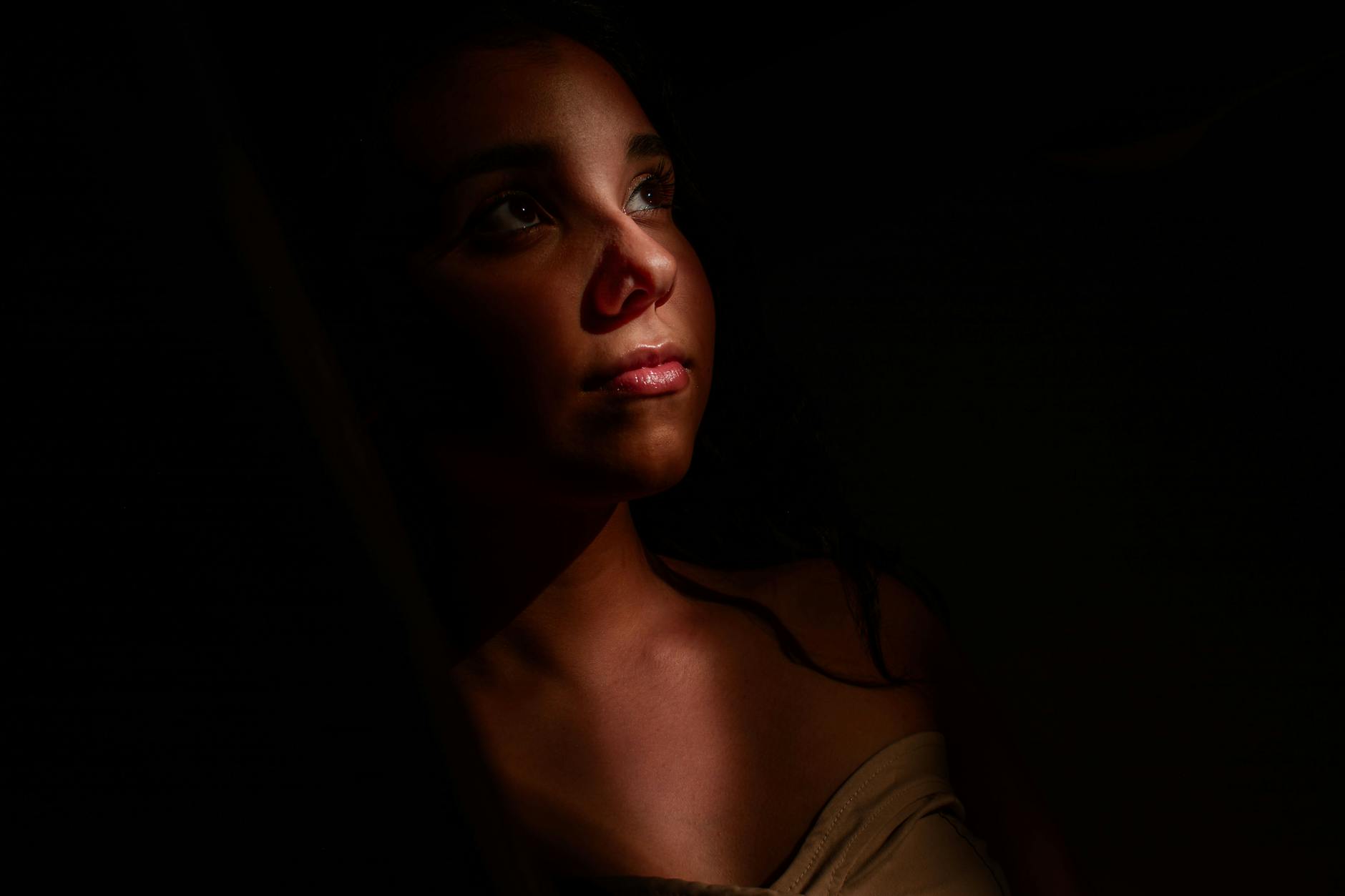 Dramatic low light portrait of a woman gazing upwards, highlighting expressive emotions. -- pijushsaha.com