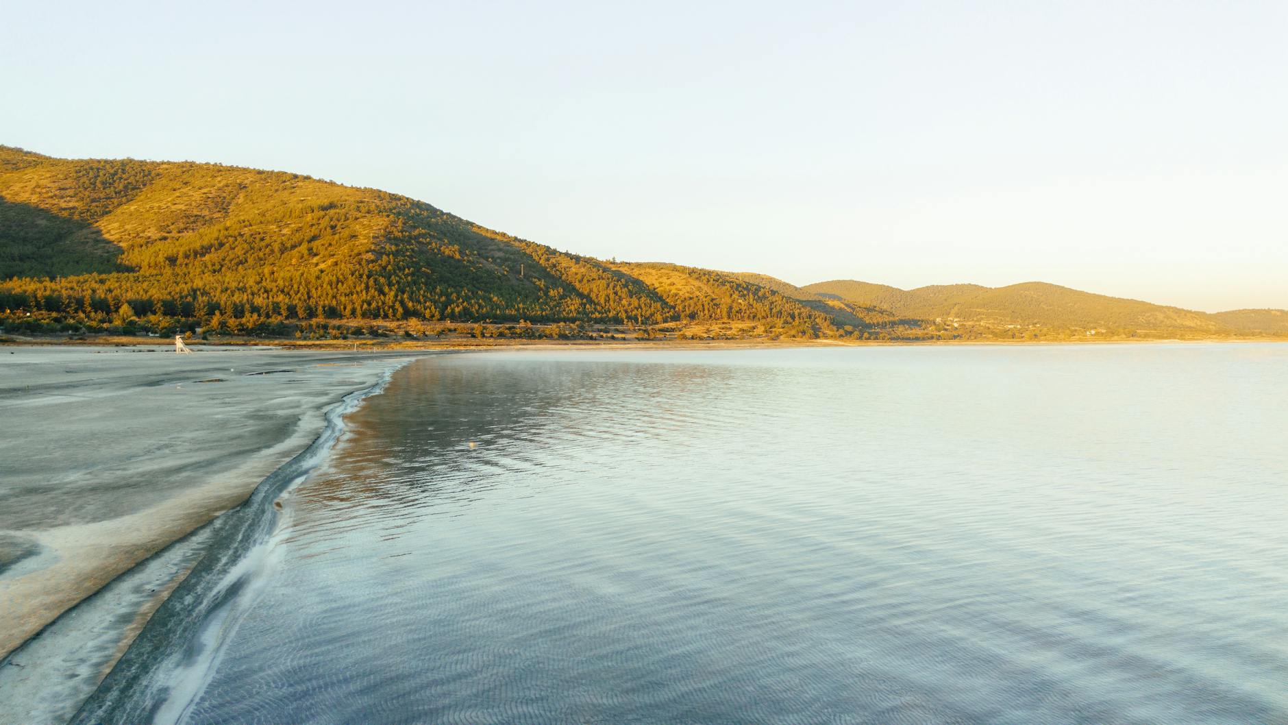 A breathtaking aerial view of a lake and mountains bathed in golden hour light, showcasing the serene beauty of nature. -- pijushsaha.com