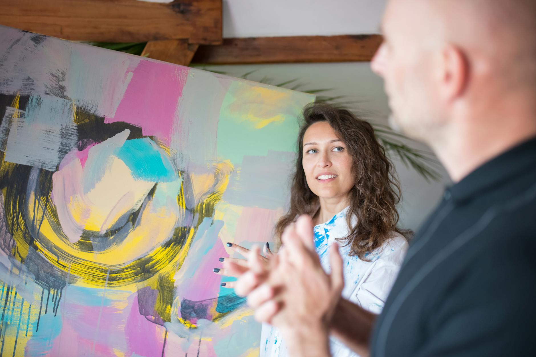 Two adults discuss vibrant abstract painting in a studio. Creative interaction captured. -- pijushsaha.com