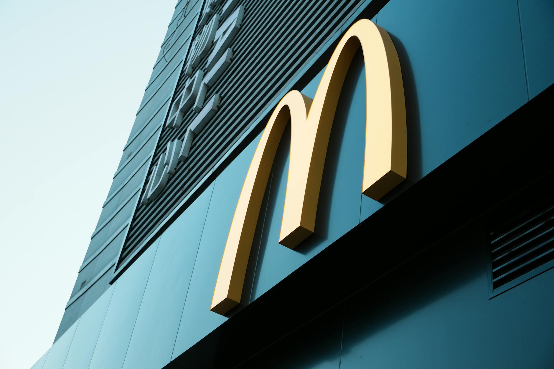 Large fast food restaurant golden arch sign on a modern building facade. — pijushsaha.com