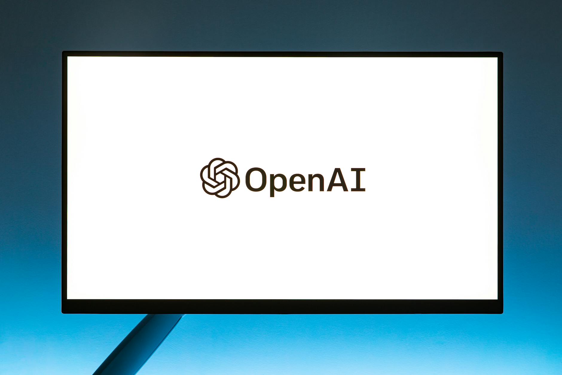 Minimalistic display of OpenAI logo on a monitor with a gradient blue background, representing modern technology. — pijushsaha.com