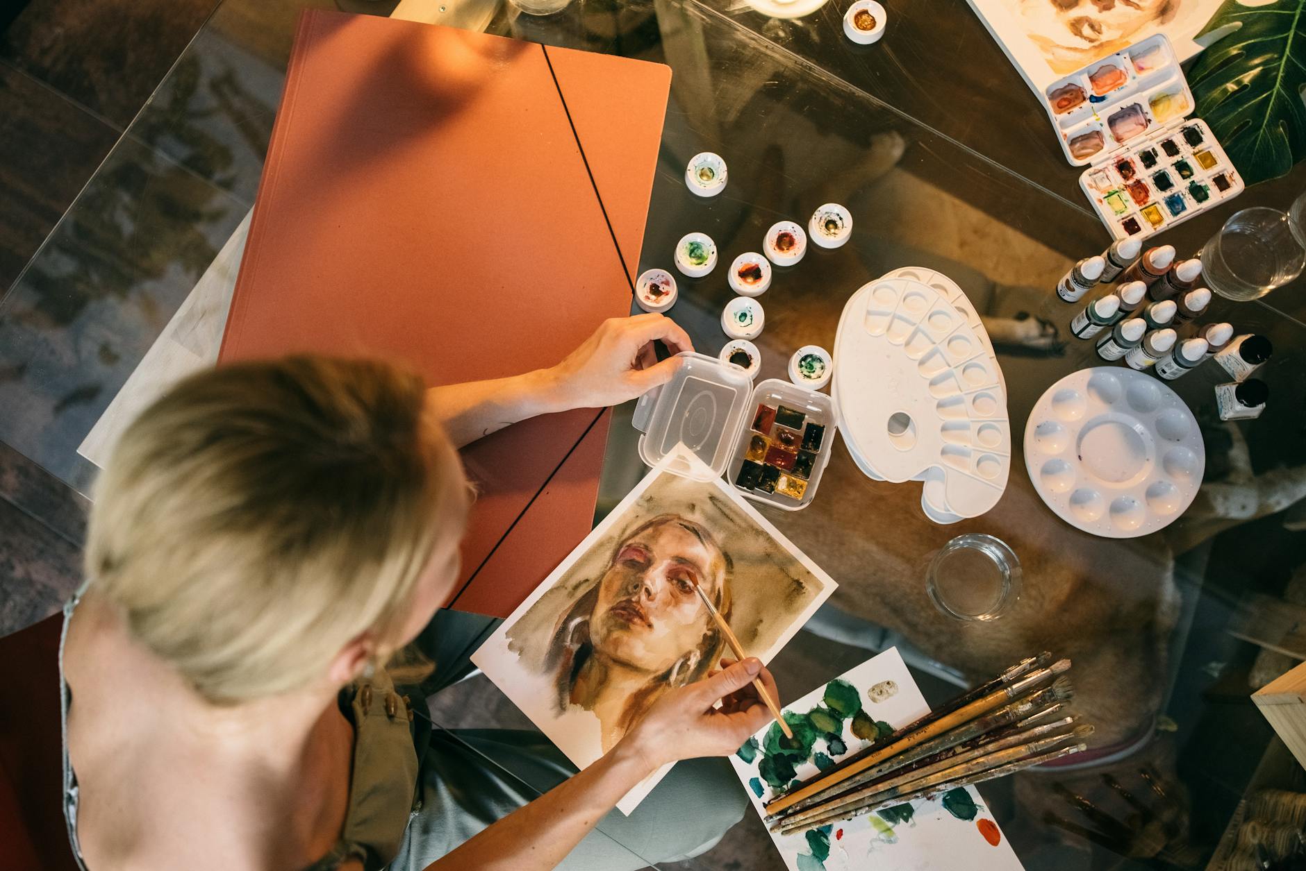 High angle view of a woman painting a portrait using watercolors inside a studio. -- pijushsaha.com