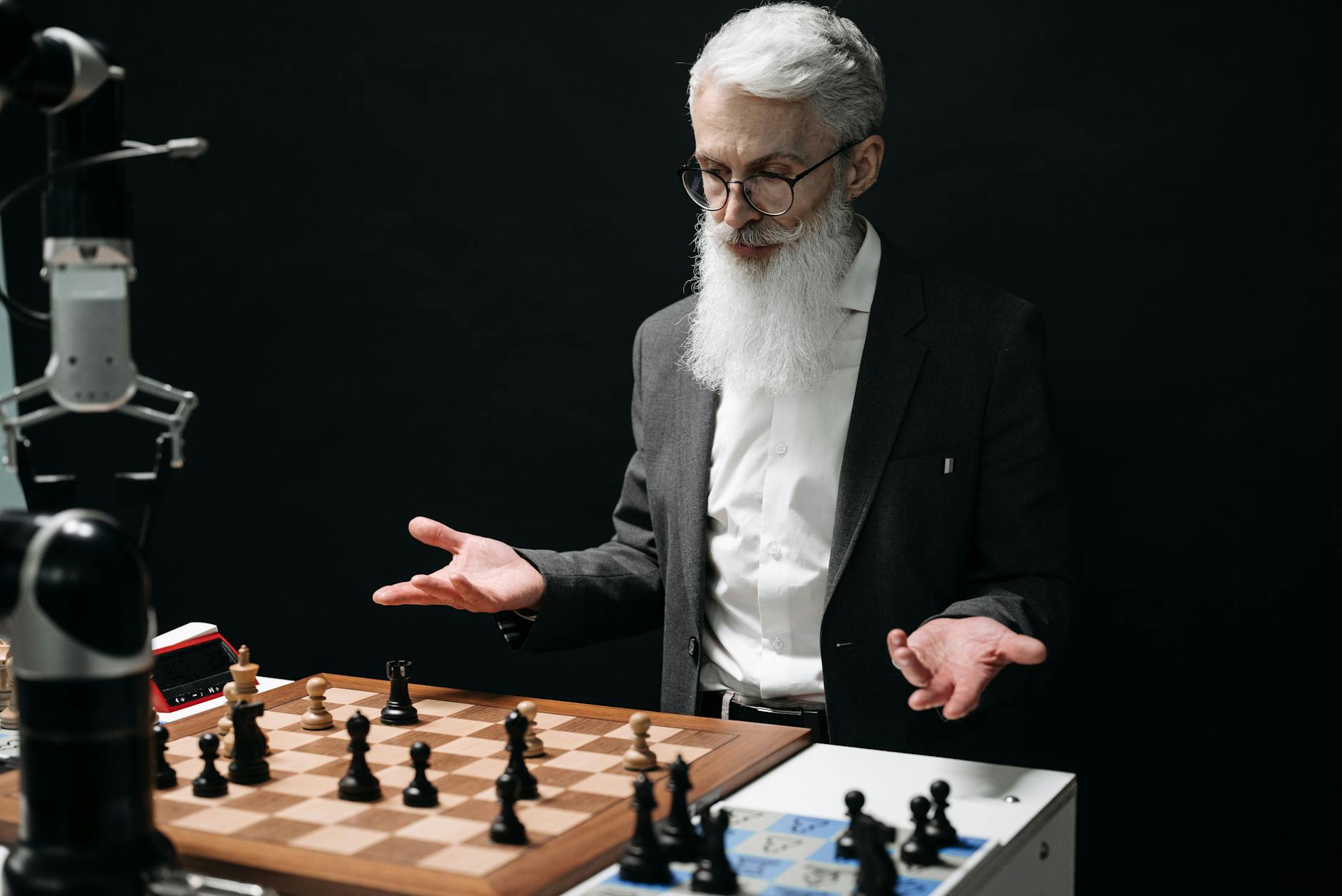 A senior man plays chess against a robot, mixing tradition with modern technology. — pijushsaha.com