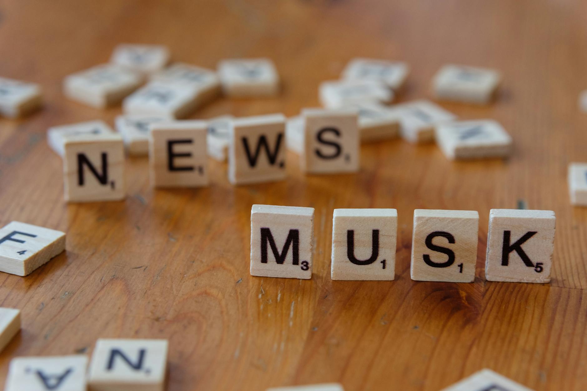 Close-up of wooden letter tiles on a table spelling 'News Musk', concept of media coverage. — pijushsaha.com