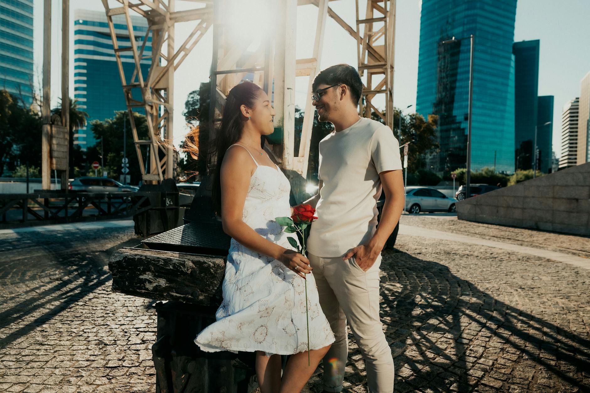 A romantic couple sharing a moment outdoors in Buenos Aires, holding a red rose under the city skyline. -- pijushsaha.com