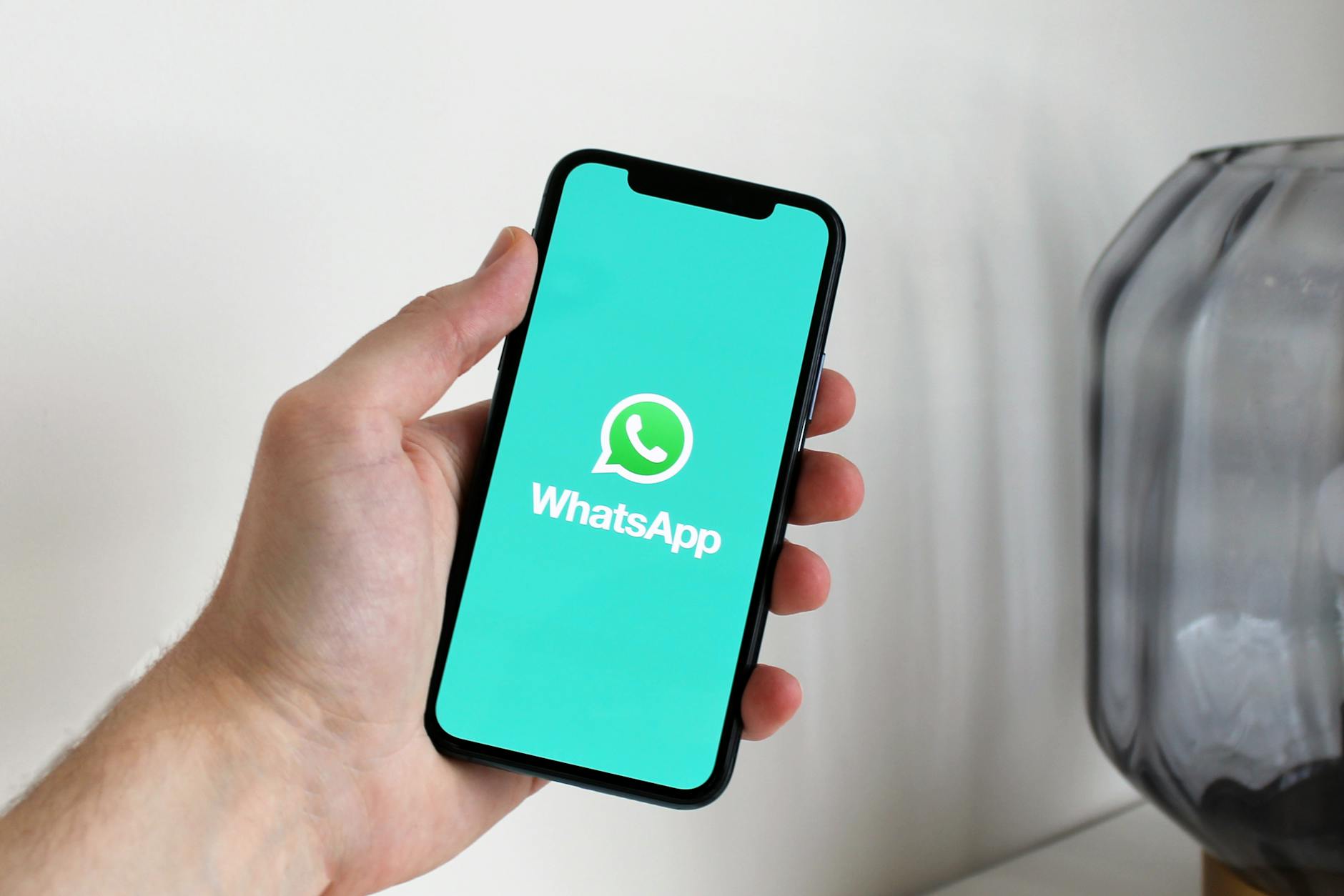 Close-up of a hand holding a smartphone displaying the WhatsApp app screen. — pijushsaha.com
