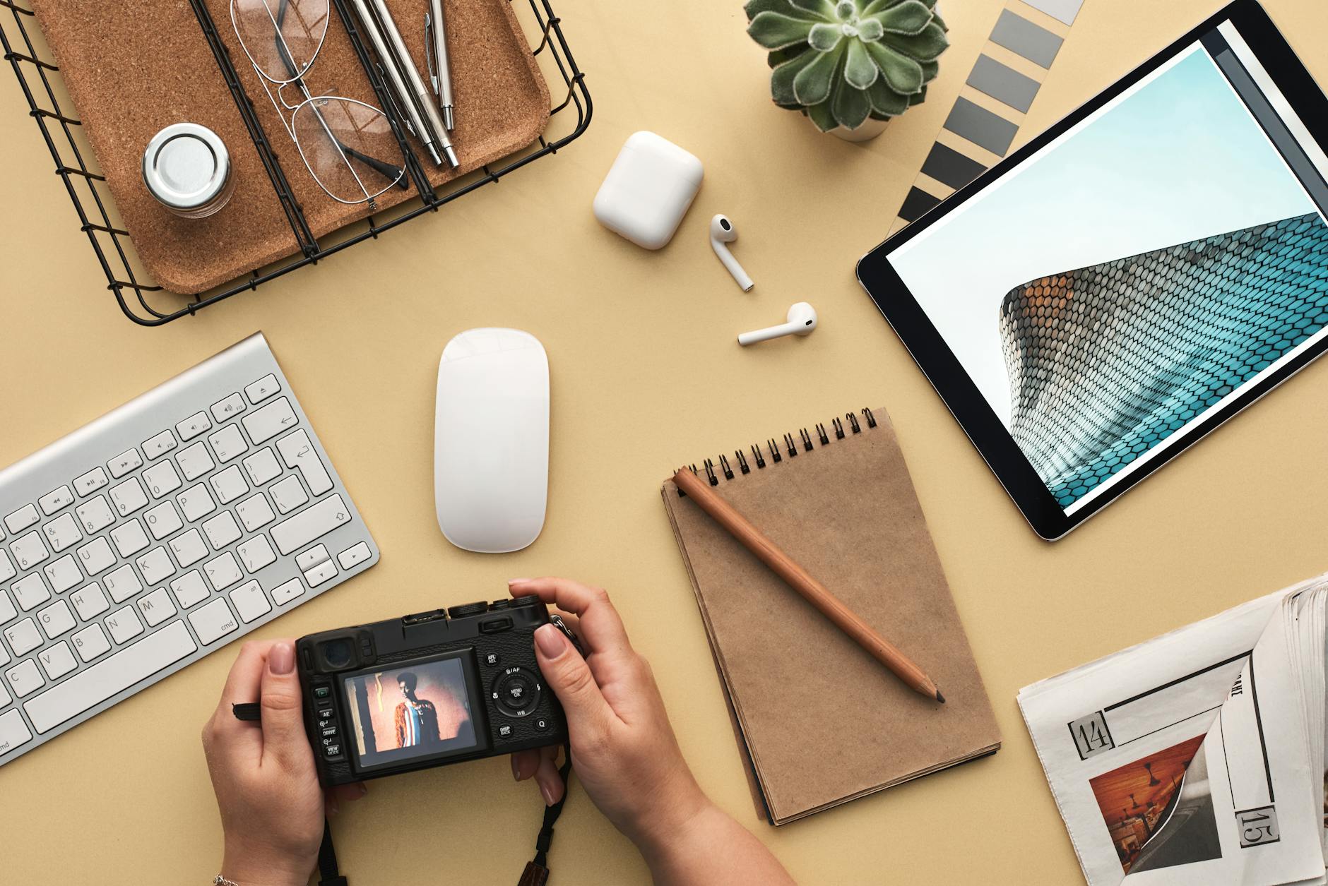 Overhead view of a modern workspace featuring tech gadgets, a camera, and a notepad. -- pijushsaha.com